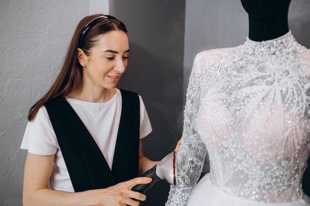 Frauen bügeln Hochzeitskleid im Studio mit Bügelmaschine Hochzeitskonzept