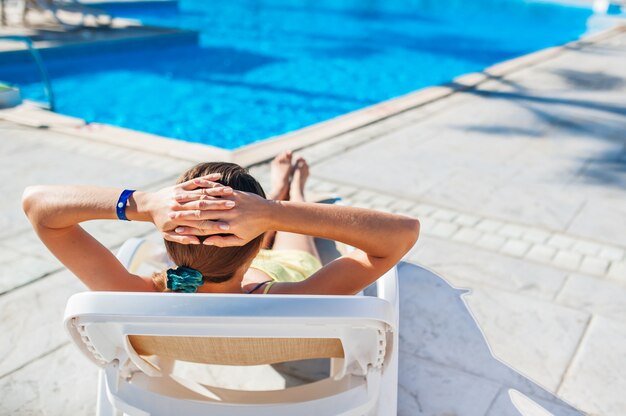 Frauen-chaiselongue auf dem hintergrund des pools am hotel