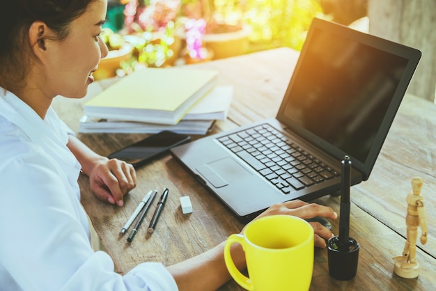 Frauen, die an der hölzernen Tabelle mit einem Laptop arbeitend sitzen