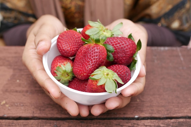 Frauen, die eine Schüssel reife rote Erdbeeren halten