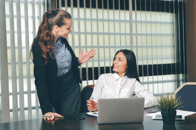 Frauen, die Finanzdokumente im Laptop am Tisch suchen