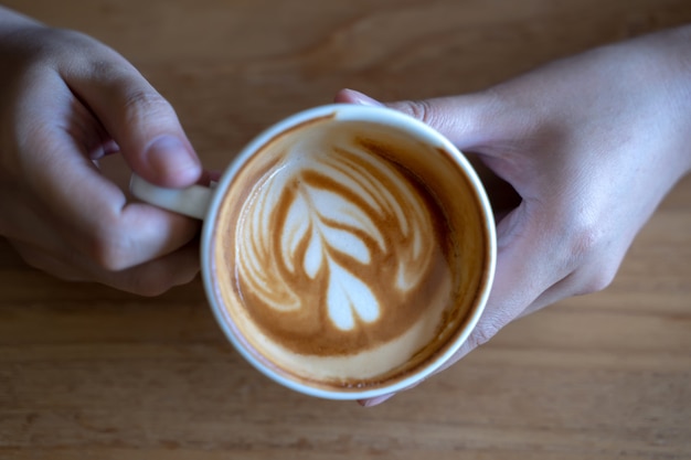 Frauen, die Kaffeetasse, Holztischcafé beim Trinken des Kaffees halten