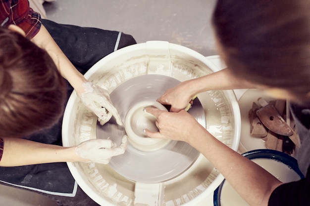 Frauen, die keramische Tonwaren, Konzept für Werkstatt und Meisterklasse, Nahaufnahme mit vier Händen machen