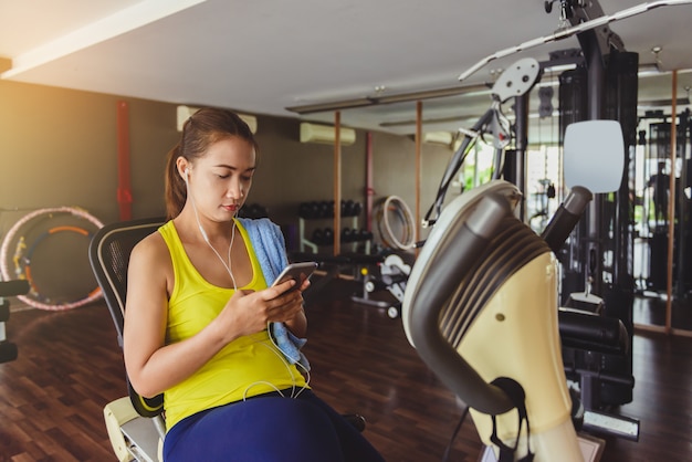 Frauen, die Smartphone in der Eignunggymnastik verwenden