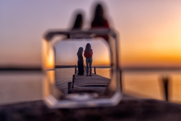 Foto frauen, die während des sonnenuntergangs auf einem pier über dem meer stehen und durch geometrische formen gesehen werden