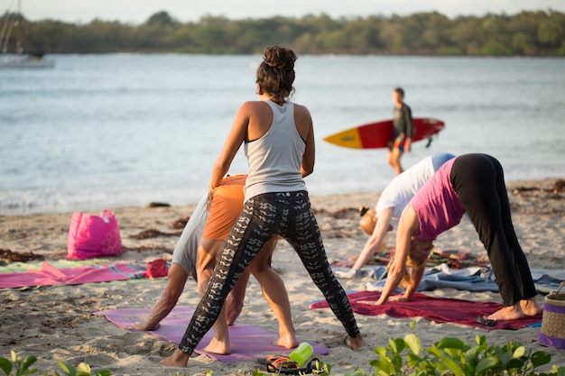 Frauen, die Yogaübungen oder unterstützte Taubenhaltung auf einem leeren Strand des Indischen Ozeans in Mauritius machen