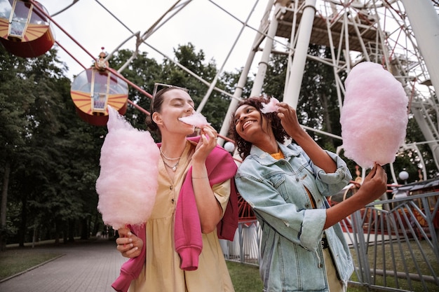 Frauen, die Zuckerwatte essen, mittlerer Schuss