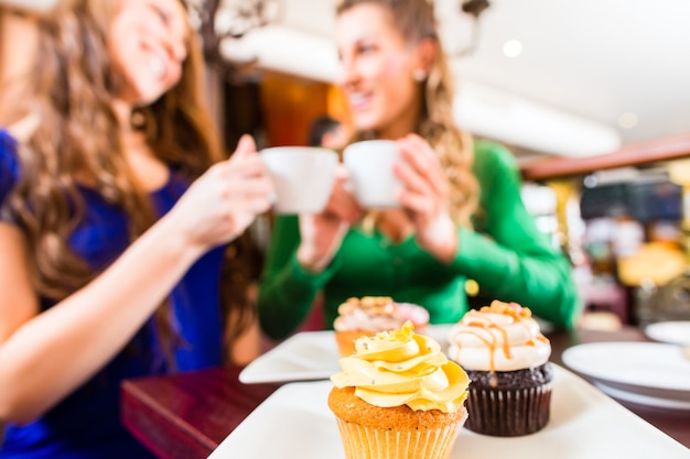 Frauen essen Muffins beim Kaffeetrinken