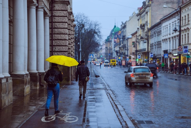 Frauen gehen nebenbei mit gelbem Regenschirm Regenwetter in der alten europäischen Stadt