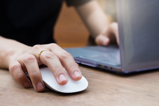 Frauen-Hände, die Laptop und drahtlose Maus verwenden