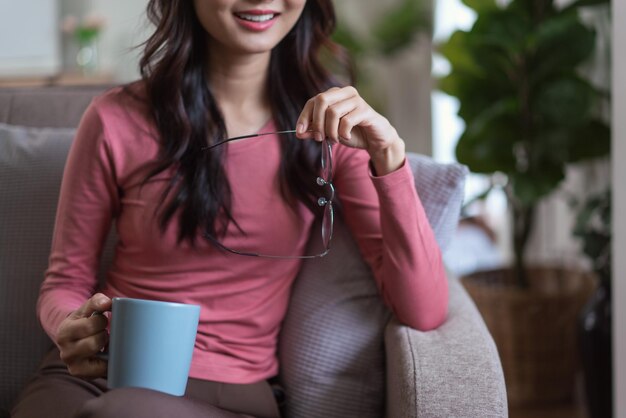 Frauen halten Gläser und Kaffeetasse in der Hand, während sie nach draußen schauen, und genießen den verträumten Lebensstil zu Hause