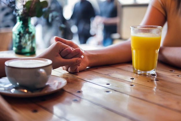 Frauen halten sich an einem Tisch in einem Café an den Händen