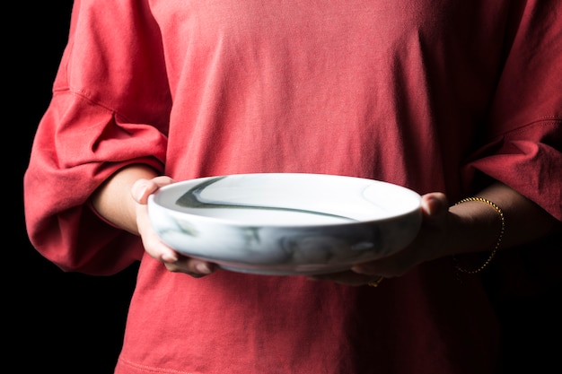 Frauen halten weiße Teller in der Hand.