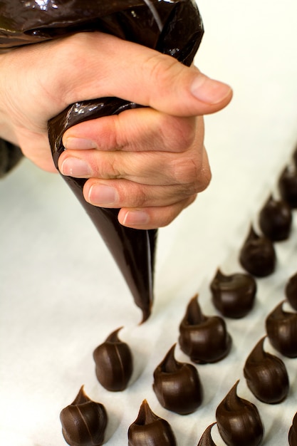 Foto frauen-hand, die schokoladen-trüffel mit einer einsetzbaren rohrbeutel vorbereiten