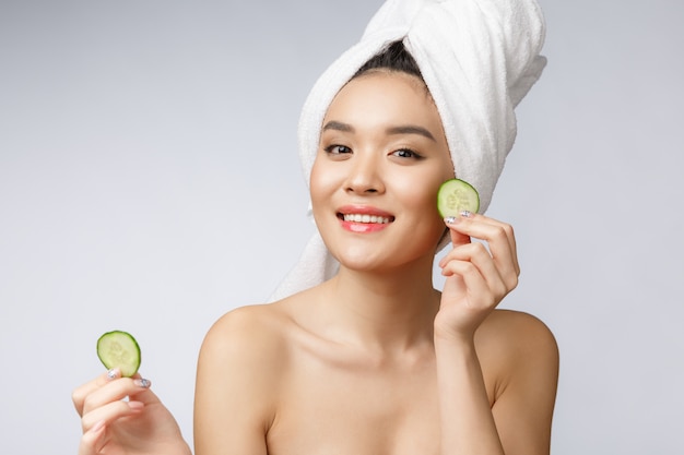 Frauen-Hautpflegebild der Schönheit junge asiatische mit Gurke auf weißem Hintergrundstudio.