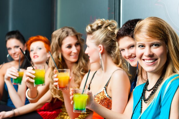 Frauen im Club oder in der Disco trinken Cocktails