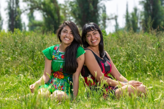 Frauen in indigener Kleidung von Xochimilco in Chinampa, die auf Gras ruhen