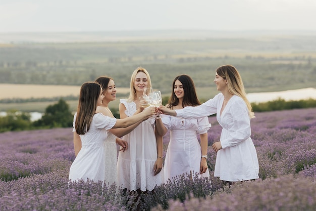 Frauen in weißen Kleidern stoßen in einem Lavendelfeld an