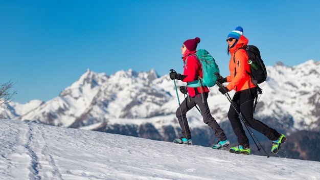 Frauen laufen mit Steigeisen auf dem Schnee in den Bergen