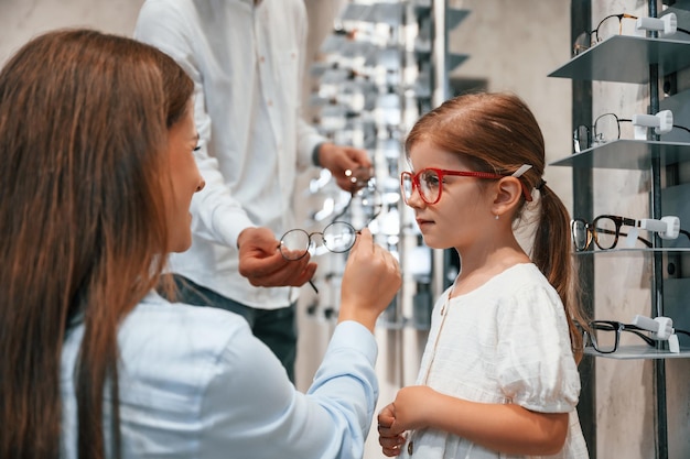 Frauen, Männer und kleine Mädchen wählen die richtige Brille zur Korrektur des Sehvermögens