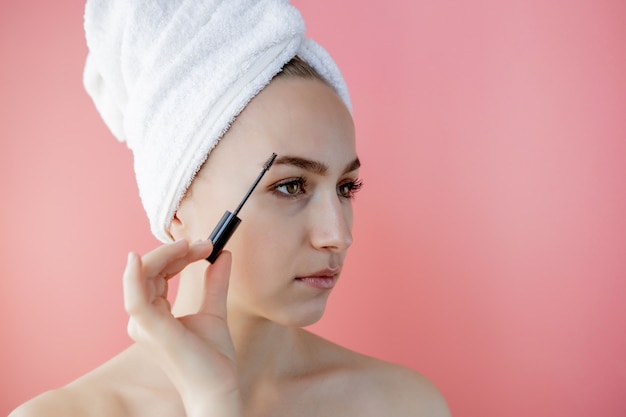 Frauen Make-up. Nahaufnahme des jungen weiblichen Modellgesichtes mit glatter weicher gesunder Haut und frischem Make-up. Schöne Mädchenhand mit Augenbrauen-Gel-Bürste für Augenbrauen. Schönheitswerkzeuge. Hochauflösendes Bild.