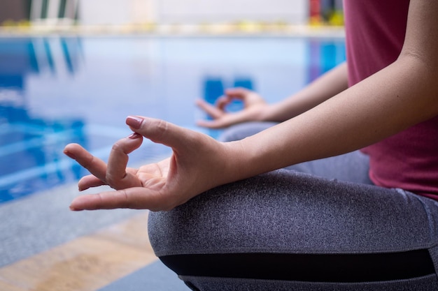 Frauen meditieren ruhig am Pool Frau macht Yoga-Pose und praktiziert Seelenfrieden Yoga-Konzept