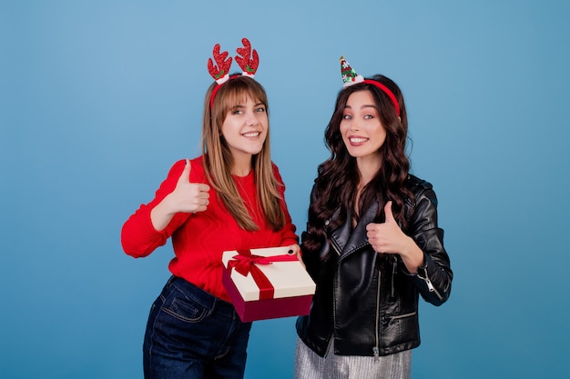 Frauen mit Geschenkbox mit dem Band, welches die lustigen Weihnachtsbänder lokalisiert über Blau trägt