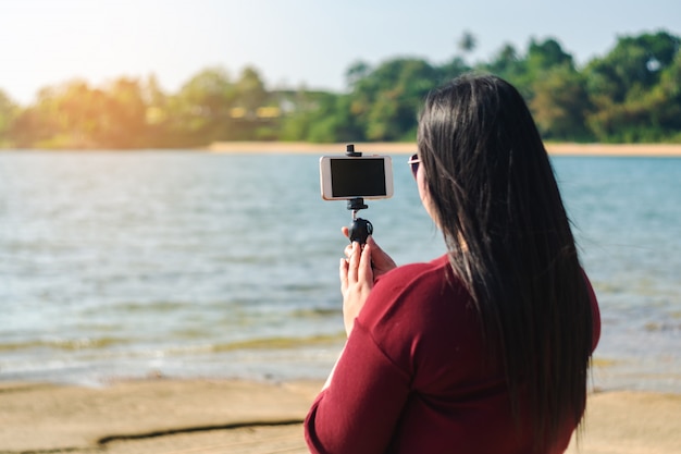 Frauen mit intelligentem Telefonmobile im Meerblicknaturhintergrund