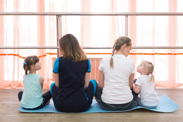 Frauen mit Kindern sitzen und schauen in ein großes Fenster.