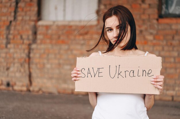 Frauen mit Plakat Save Ukraine Eine Frau mit kriegerischem Blick blickt in die Kamera