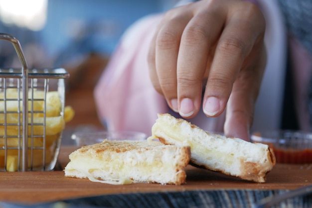 Frauen pflücken von Hand Sandwich mit Schinken-Käse-Tomaten