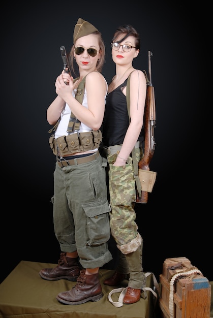 Frauen posieren in Militäruniform und Waffen