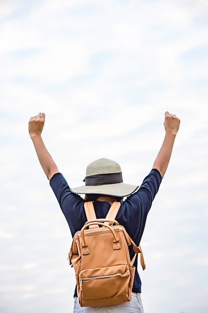 Frauen schultern Rucksack und heben ihre Arme in den Himmel.