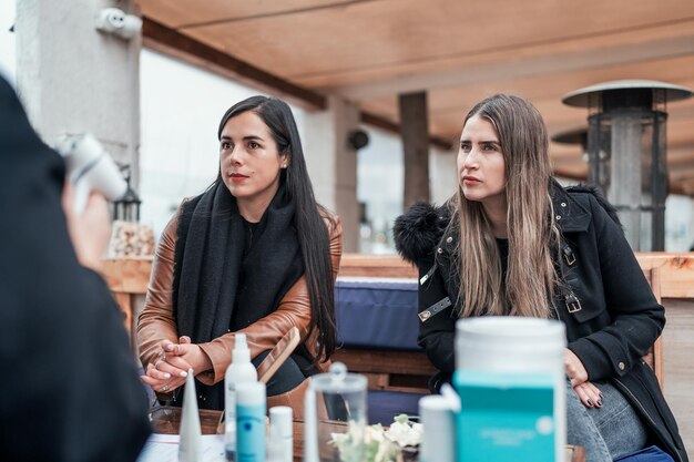 Foto frauen sitzen an einem tisch mit dermatologischen produkten und schauen oder hören kunden zu