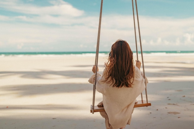 Frauen sitzen auf Schaukeln in der Nähe des Meeresstrandes bei Sonnenschein