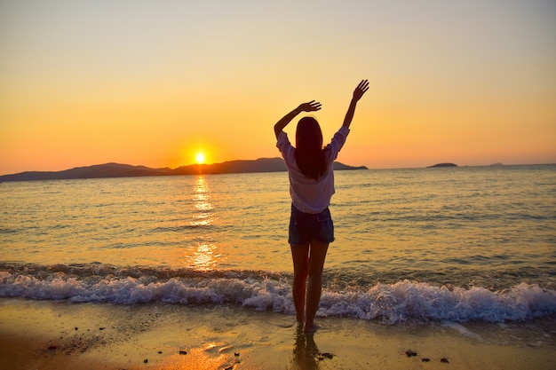 Frauen stehen am Strand am Meer und Sonnenuntergang