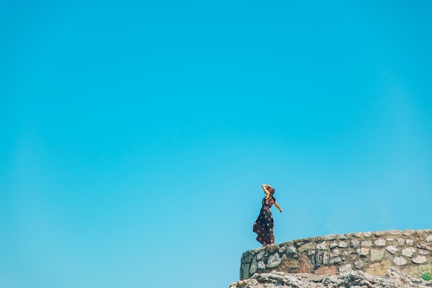 Frauen stehen an sonnigen Tagen in hellem Kleid auf der Klippe