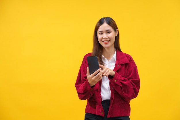 Frauen surfen mit dem Smartphone in sozialen Medien und lächeln glücklich über isolierten gelben Hintergrund