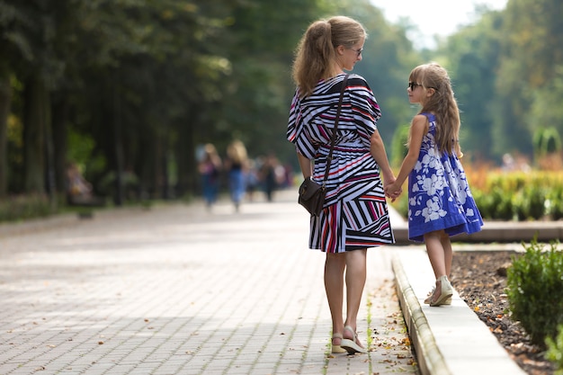 Frauen- und Kindermädchenhändchenhalten draußen.