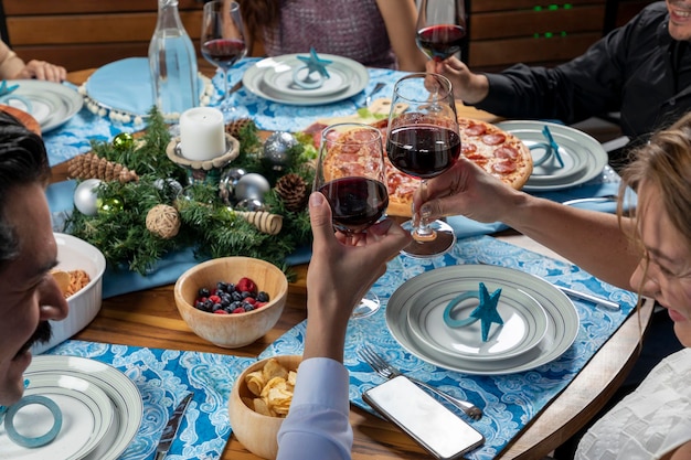 Frauen- und Mannhand, die ein Glas beim Toasten bei einem Weihnachtsessen hält