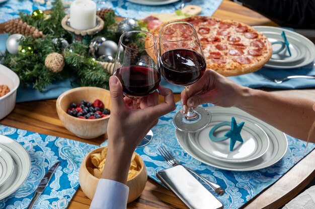 Frauen- und Mannhand, die ein Glas beim Toasten bei einem Weihnachtsessen hält