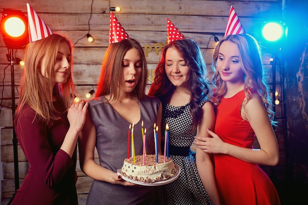 Frauen zünden Kerzen auf dem Kuchen mit Champagner in der Hand an