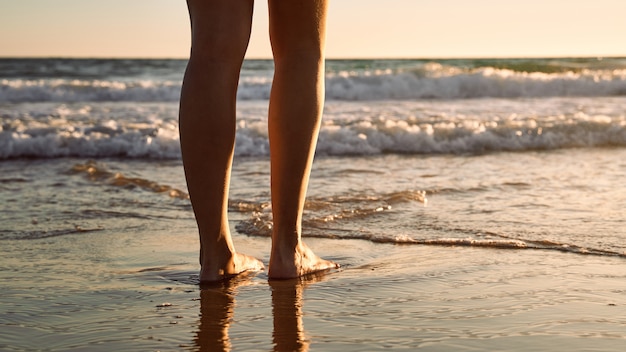 Frauenbeine am Strand bei Sonnenuntergang