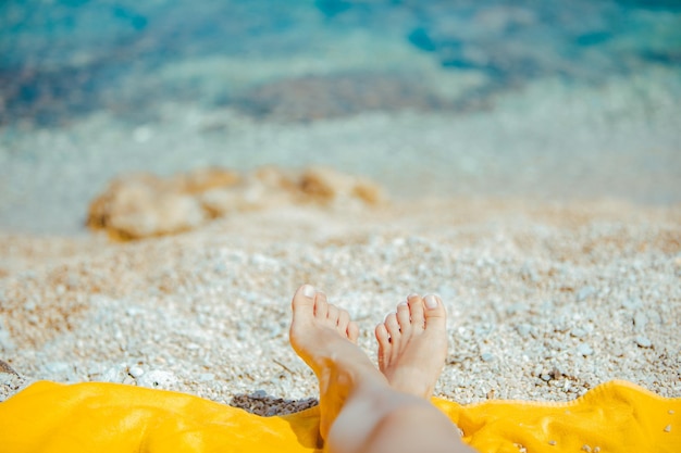 Frauenbeine auf gelber Decke am Sonnenstrand aus nächster Nähe