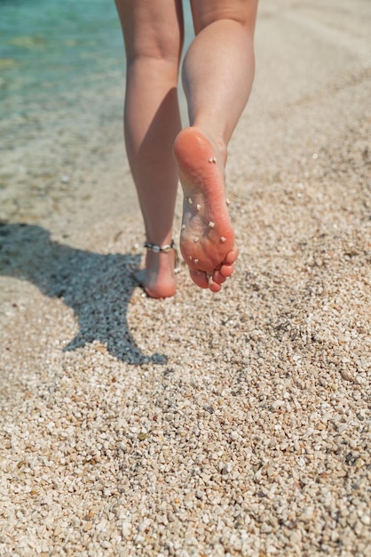 Frauenbeine barfuß zu Fuß durch den Sommerurlaub am Strand