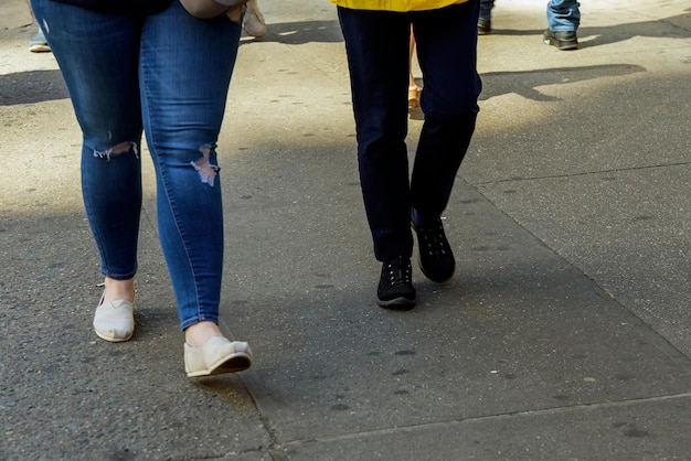 Frauenbeine, die an einem sonnigen Tag auf einem Fußgängerüberweg laufen