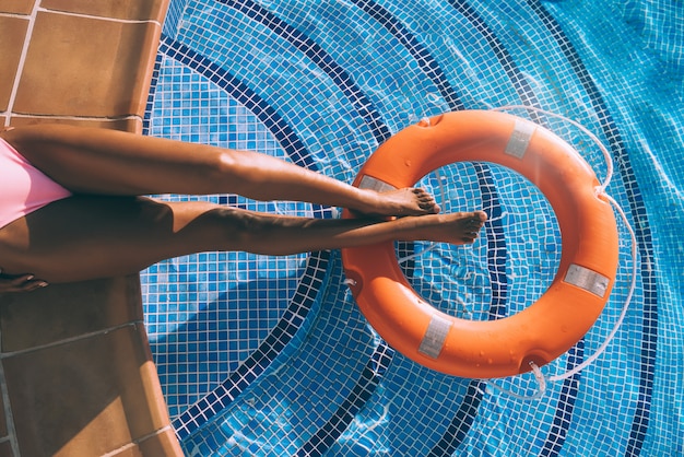 Frauenbeine in einem Schwimmbad mit Lebensretter