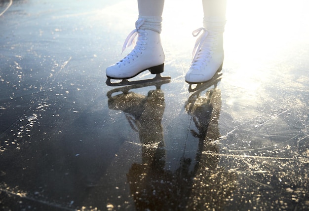 Foto frauenbeine in weißen schlittschuhen auf einer eisbahn im freien. ... menschen-, wintersport- und freizeitkonzept.