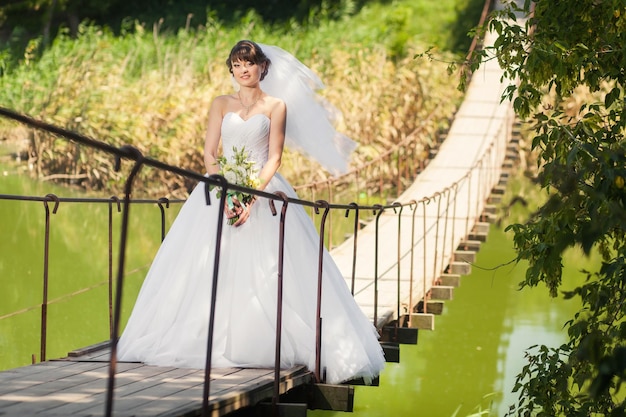 Frauenbraut, die auf der Brücke über dem Fluss steht