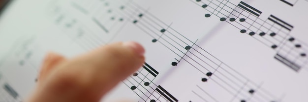 Foto frauenfinger zeigt auf musiknoten klassische musik und musikausbildungskonzept